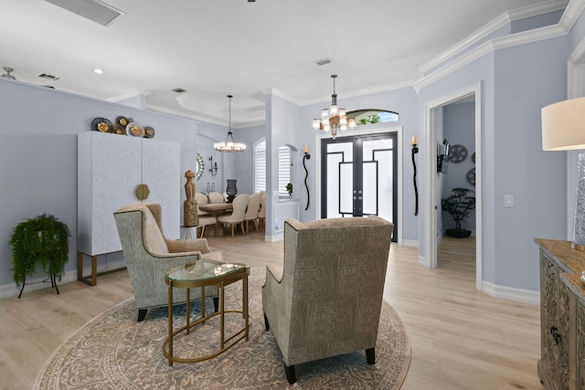 sitting room featuring ornamental molding, light wood-type flooring, and a chandelier