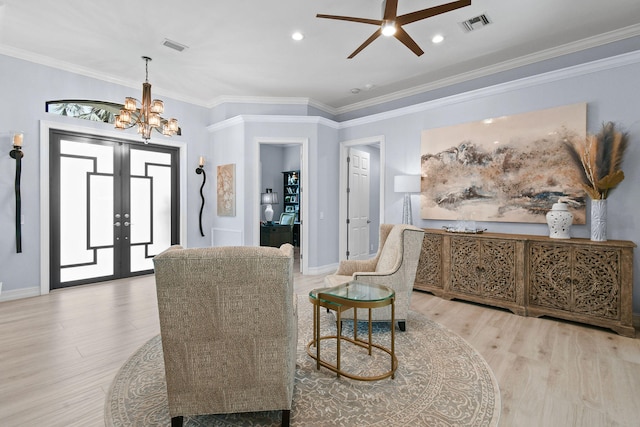 living area featuring light wood-type flooring, french doors, ceiling fan with notable chandelier, and ornamental molding