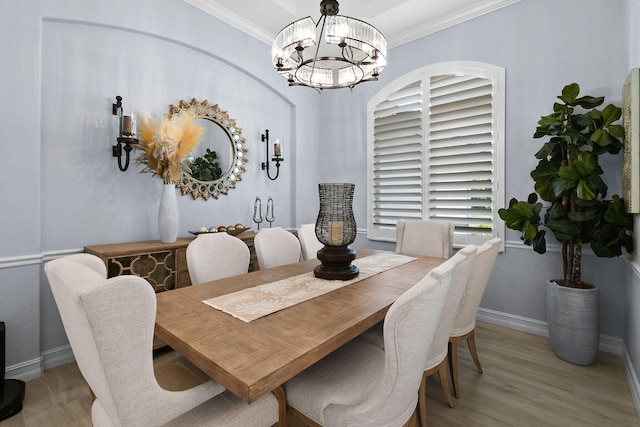 dining area with light hardwood / wood-style floors, an inviting chandelier, and ornamental molding