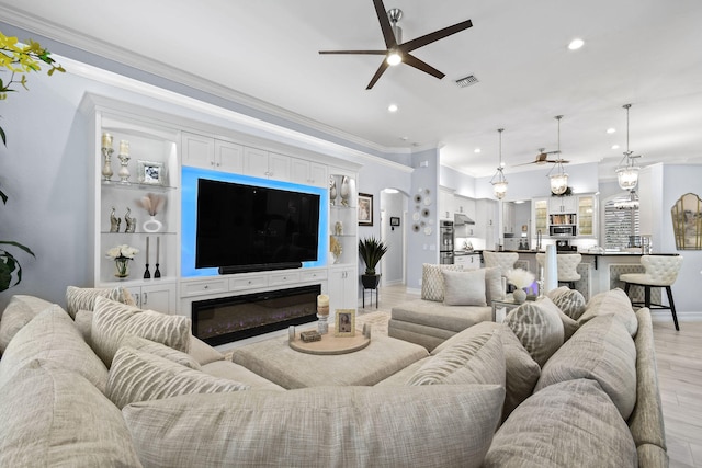 living room with ceiling fan, ornamental molding, and light wood-type flooring