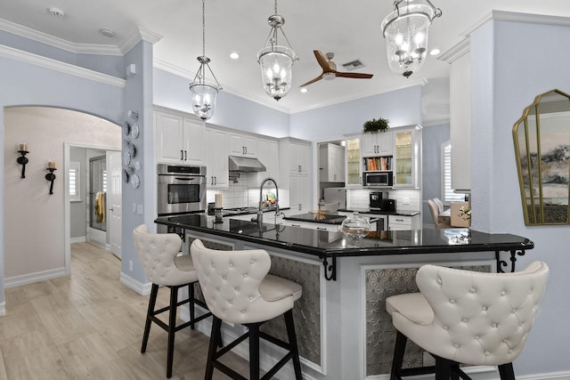 kitchen featuring pendant lighting, appliances with stainless steel finishes, a breakfast bar, decorative backsplash, and white cabinets