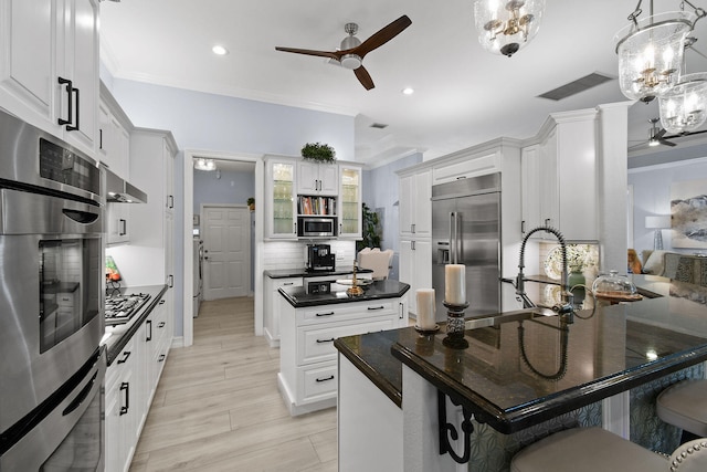 kitchen with light wood-type flooring, pendant lighting, ceiling fan with notable chandelier, stainless steel appliances, and white cabinets