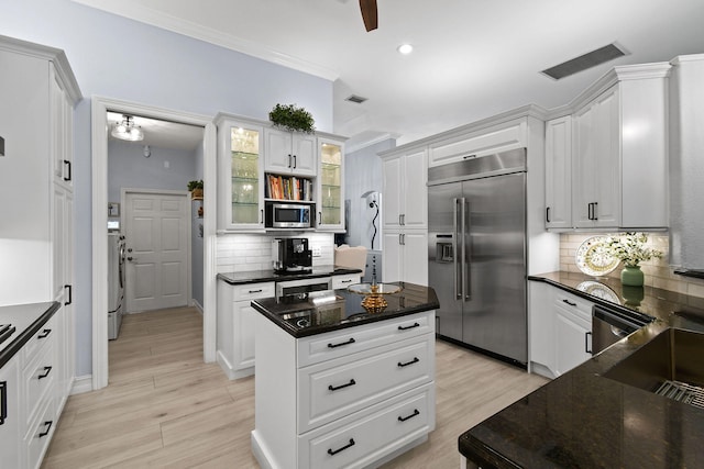 kitchen featuring white cabinets, backsplash, light wood-type flooring, appliances with stainless steel finishes, and a kitchen island