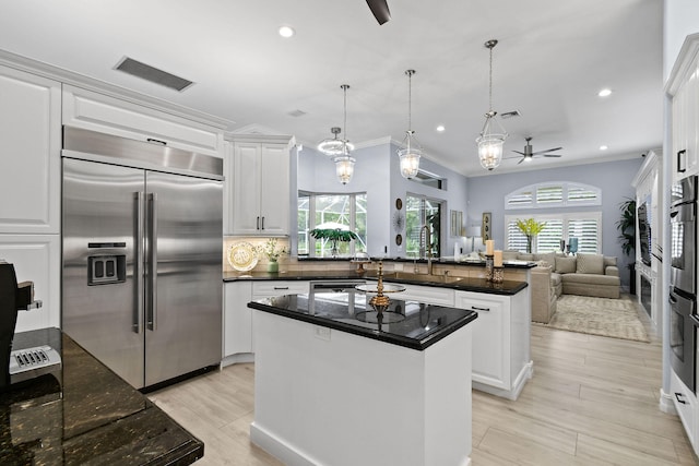 kitchen featuring stainless steel appliances, decorative light fixtures, a kitchen island, ceiling fan, and white cabinets