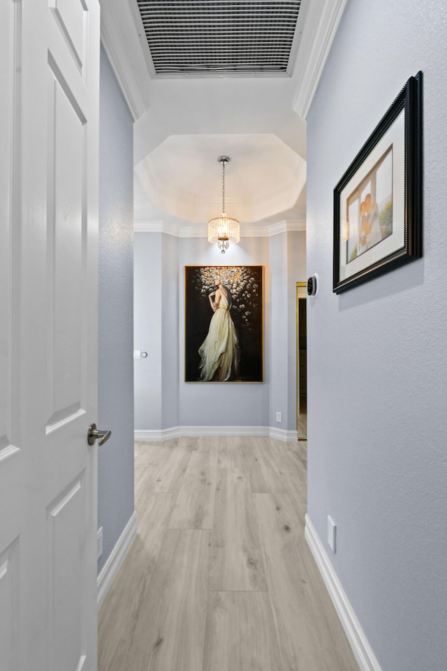 hallway with light hardwood / wood-style flooring, ornamental molding, and a chandelier