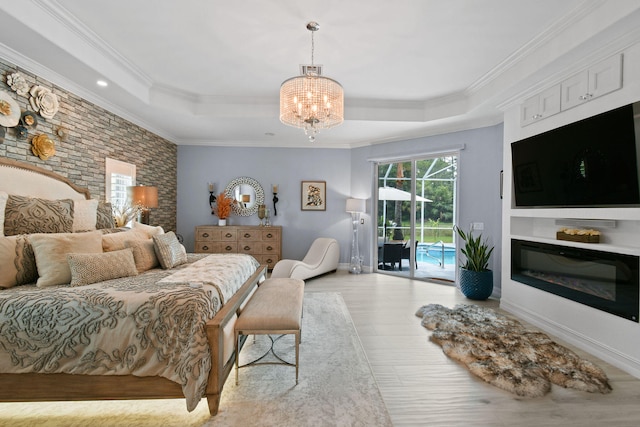 bedroom featuring light wood-type flooring, crown molding, a tray ceiling, and access to exterior