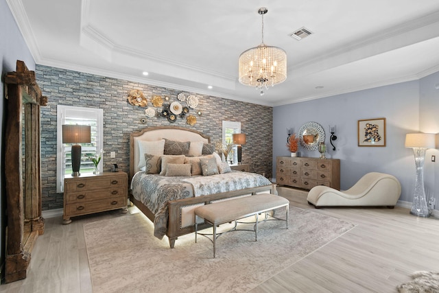 bedroom featuring light hardwood / wood-style floors, an inviting chandelier, a raised ceiling, and ornamental molding