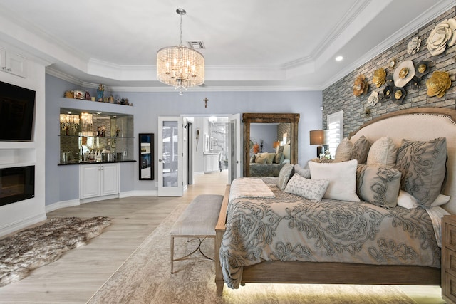 bedroom featuring ornamental molding, light hardwood / wood-style flooring, a raised ceiling, and a notable chandelier