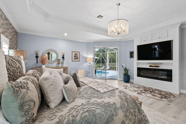 bedroom with a notable chandelier, a tray ceiling, access to outside, crown molding, and light wood-type flooring