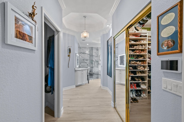 walk in closet with an inviting chandelier and light hardwood / wood-style floors