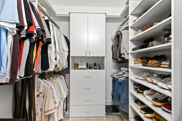 walk in closet with light hardwood / wood-style floors