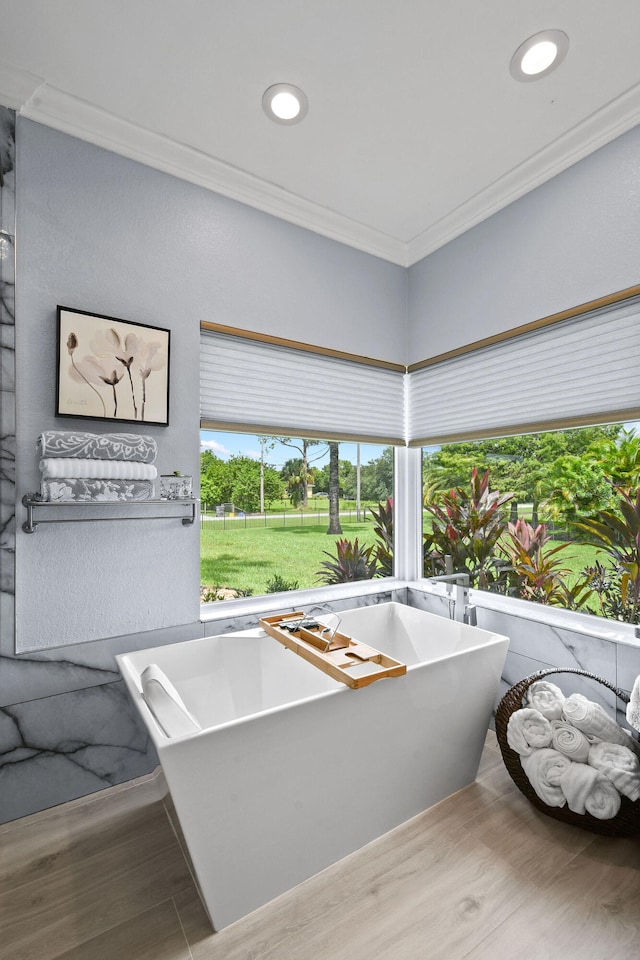 bathroom featuring a tub, hardwood / wood-style floors, and ornamental molding