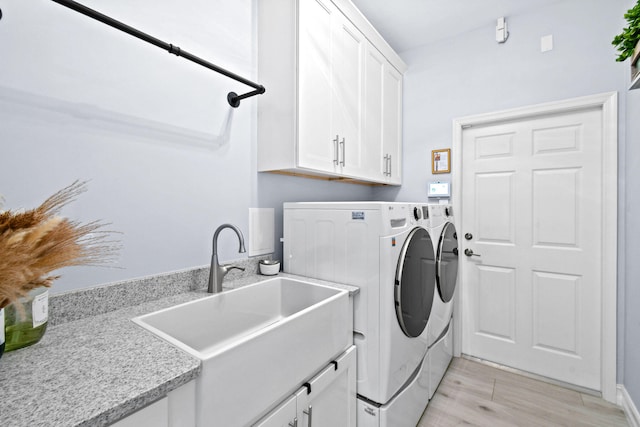 washroom with light hardwood / wood-style flooring, sink, cabinets, and washer and dryer