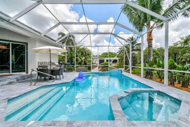 view of pool with glass enclosure, a patio area, and an in ground hot tub