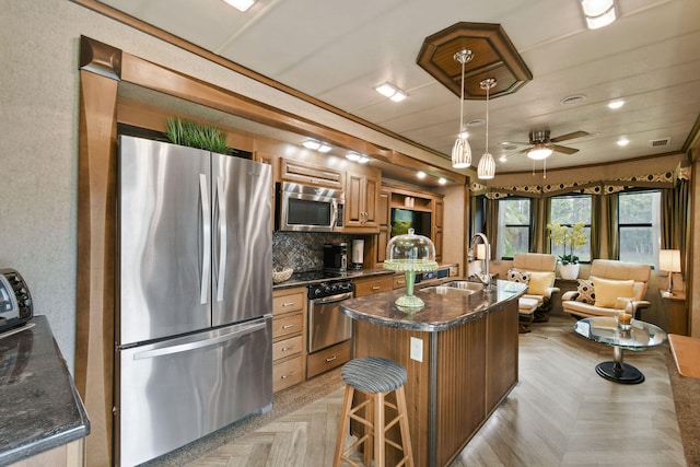 kitchen with stainless steel appliances, a center island, ceiling fan, sink, and a breakfast bar area