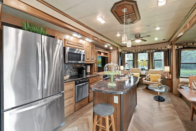 kitchen featuring a center island, appliances with stainless steel finishes, sink, ceiling fan, and a breakfast bar