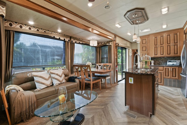 interior space with crown molding, pendant lighting, sink, and a kitchen island with sink