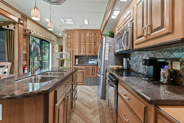 kitchen featuring hanging light fixtures, crown molding, appliances with stainless steel finishes, sink, and a center island with sink