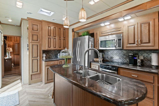 kitchen featuring decorative light fixtures, appliances with stainless steel finishes, a kitchen island with sink, crown molding, and dark stone countertops