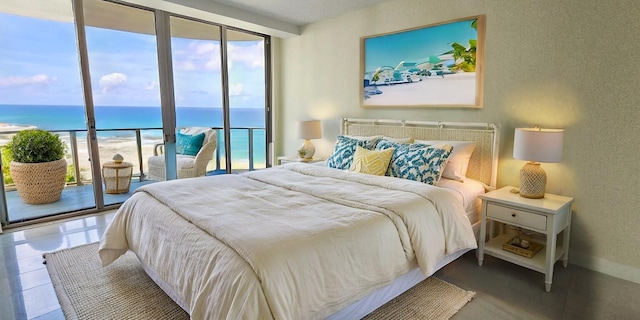 bedroom with a beach view, access to exterior, a water view, and a wall of windows