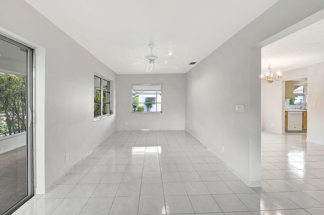 empty room with ceiling fan with notable chandelier, light tile patterned floors, and sink