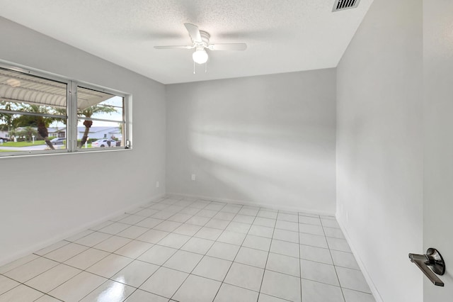 empty room with ceiling fan, light tile patterned flooring, and a textured ceiling