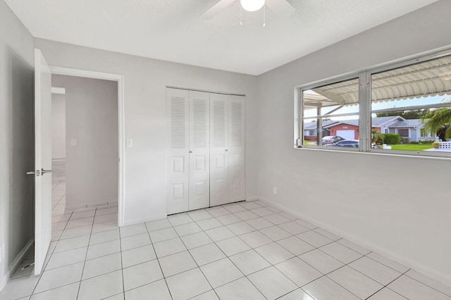 unfurnished bedroom featuring ceiling fan, a closet, and light tile patterned floors