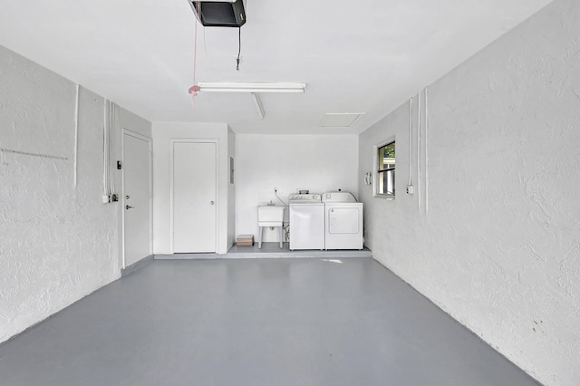 garage featuring sink, washer and dryer, and a garage door opener