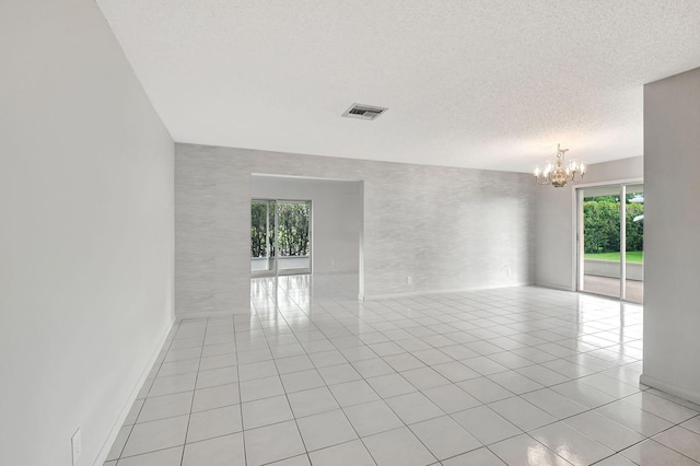 tiled spare room with a textured ceiling and an inviting chandelier