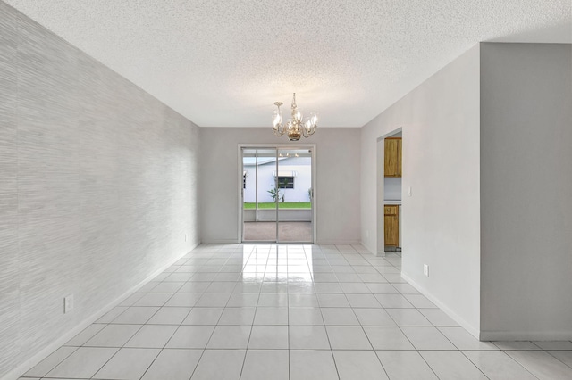 tiled empty room with a textured ceiling and an inviting chandelier