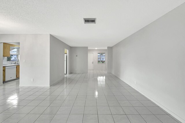 tiled empty room with a healthy amount of sunlight and a textured ceiling