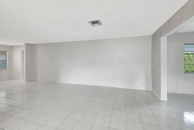 tiled empty room featuring a textured ceiling