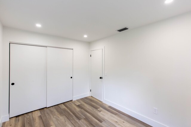 unfurnished bedroom with light hardwood / wood-style flooring and a closet