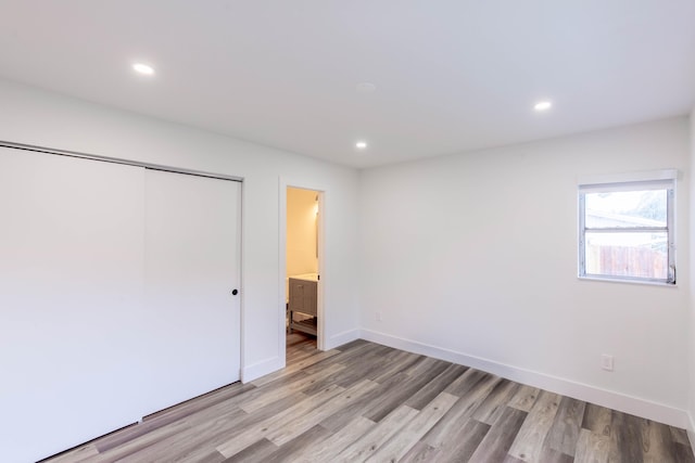 unfurnished bedroom with light wood-type flooring, a closet, and connected bathroom