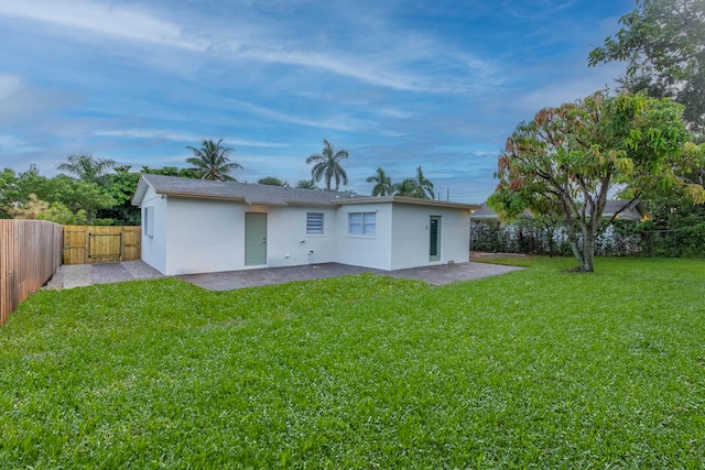 rear view of property featuring a patio area and a lawn