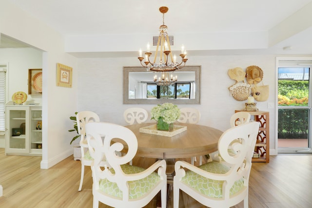 dining space with a healthy amount of sunlight, wood-type flooring, and a notable chandelier