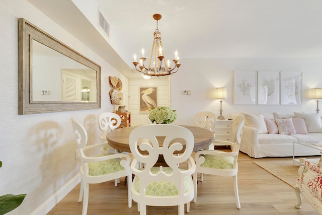 dining area with an inviting chandelier and light hardwood / wood-style flooring