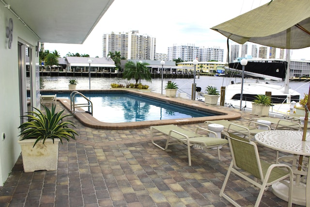 view of pool featuring a water view and a patio