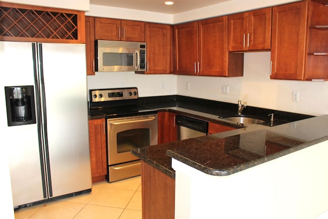 kitchen featuring dark stone counters, kitchen peninsula, sink, appliances with stainless steel finishes, and light tile patterned flooring