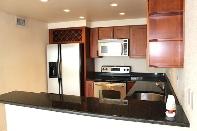 kitchen with stainless steel appliances, sink, kitchen peninsula, and dark stone counters