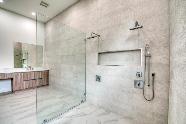 bathroom featuring tiled shower and vanity