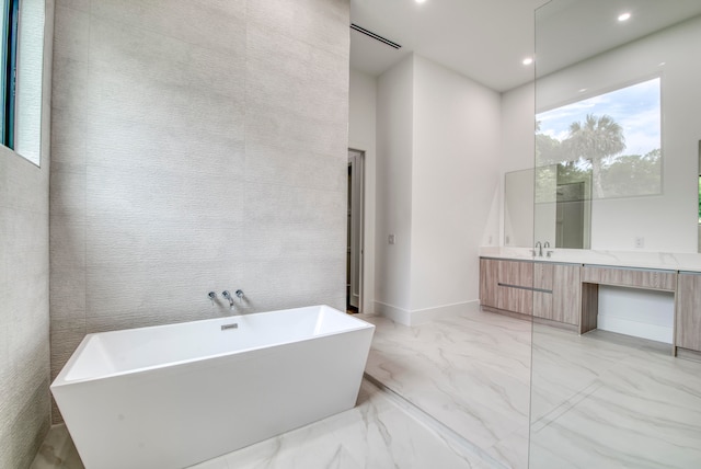 bathroom with a tub, vanity, and tile walls