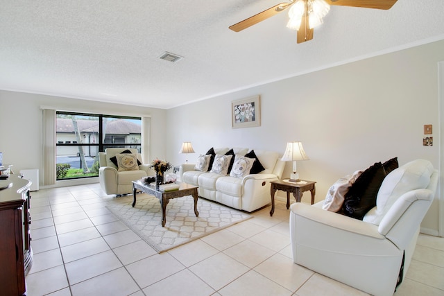 living room with a textured ceiling, light tile patterned floors, ornamental molding, and ceiling fan