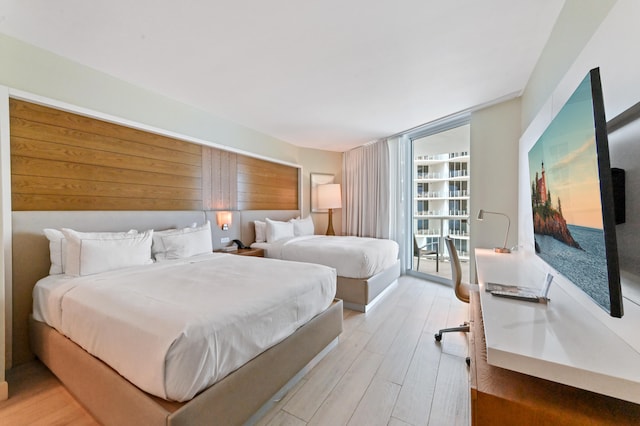 bedroom with light hardwood / wood-style floors and a wall of windows