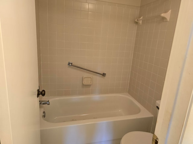 bathroom with tiled shower / bath combo and toilet