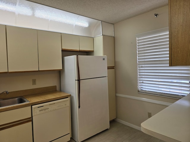 kitchen with cream cabinets, light wood-type flooring, sink, and white appliances