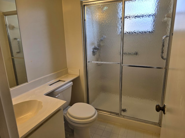 bathroom with tile patterned floors, a shower with shower door, toilet, and vanity