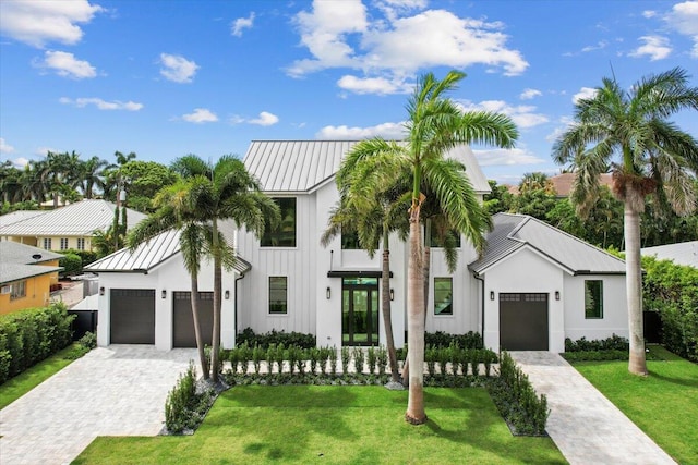 224 Edmor Rd, West Palm Beach, FL 33405 - view of front of home with a front yard, decorative driveway, an attached garage, and a standing seam roof