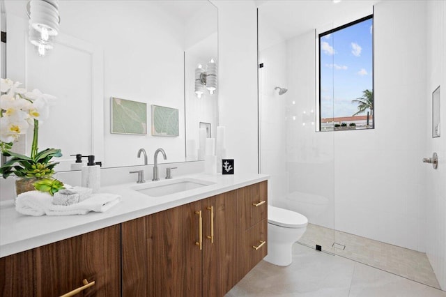 bathroom with toilet, a tile shower, and vanity