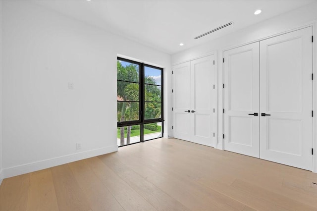 unfurnished bedroom featuring light wood-type flooring and multiple closets